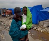 Un hombre alza a un niño en un campamento de sobrevivientes del terremoto haitiano inundado por intensas lluvias en Puerto Príncipe, viernes 19 de marzo de 2010. (AP Foto/Ramon Espinosa)