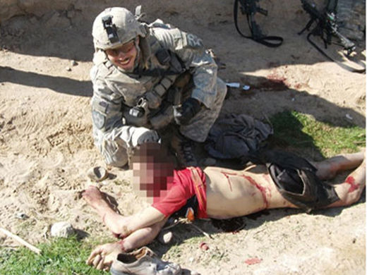 Soldados sonriendo al lado de cadaver afgáno