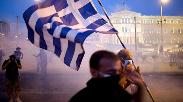 Varios manifestantes se protegen de los gases lacrimógenos lanzados por los policías antidisturbios en los aledaños del Parlamento griego, en Atenas, el 28 de junio de 2011. Foto: EFE/Arno Burgi