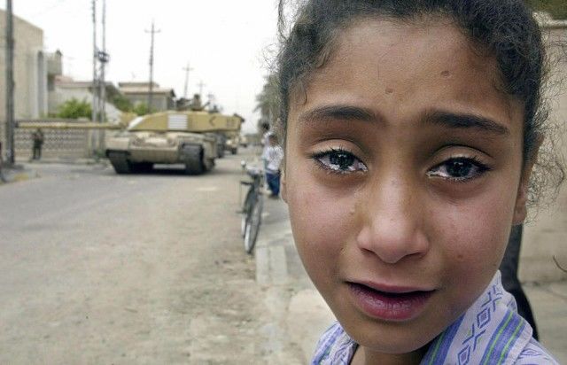 Un joven iraquí llora niña mientras un tanque Challenger británico se mueve en la oficina del partido Baaz en Basora, 08 de abril 2003. Foto: Impar Andersen / AFP / Getty Images