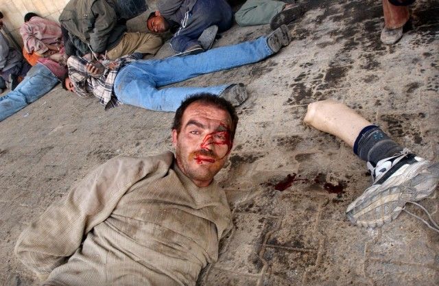Un hombre se encuentra esposado con su pierna artificial cerca de la cabeza después de infantes de marina EE.UU. los llamaran saqueadores de un banco el abril 16 de 2003 en Bagdad, Irak. Foto: Spencer Platt / Getty Images